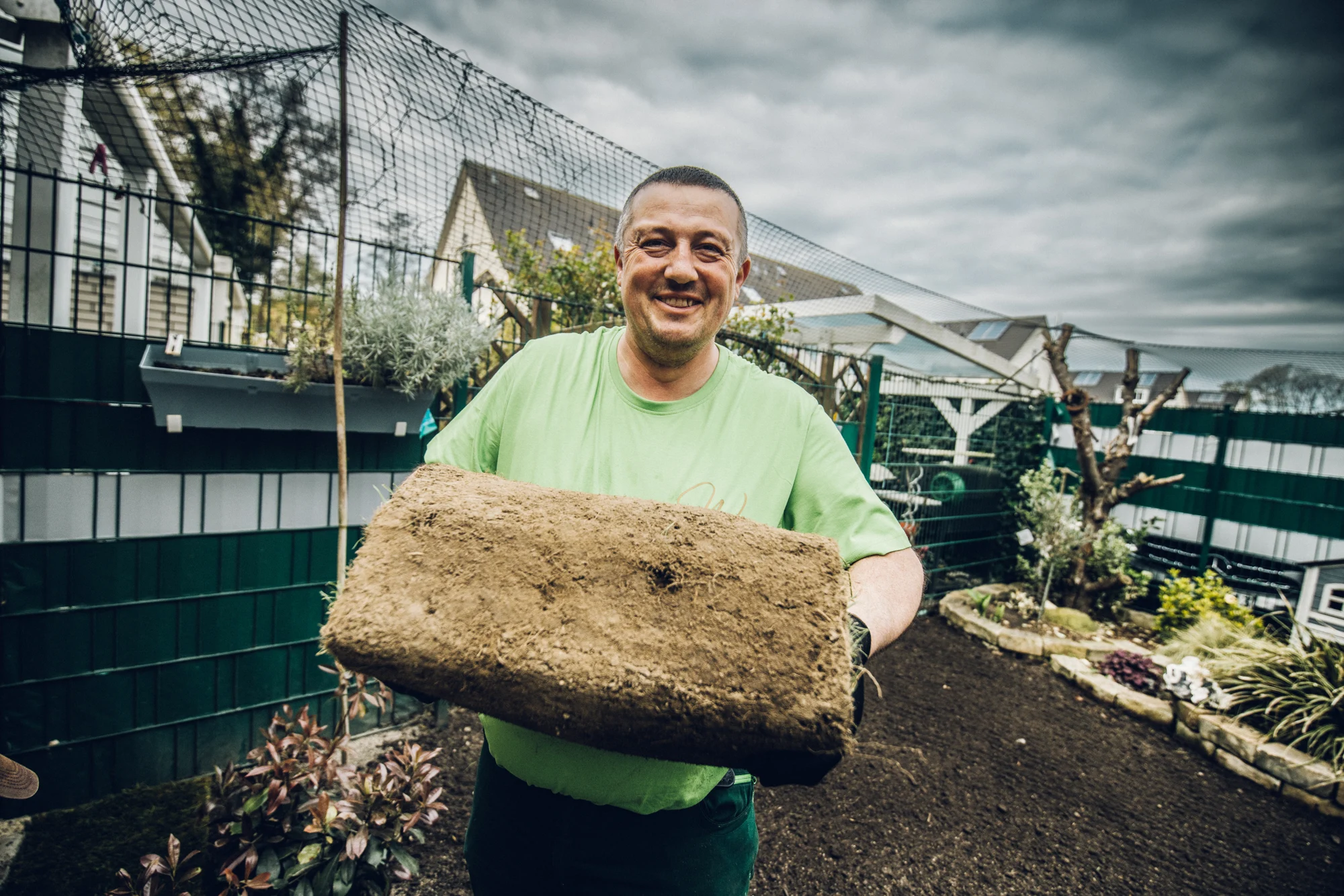 Kollege trägt eine Rolle Rollrasen im Garten
