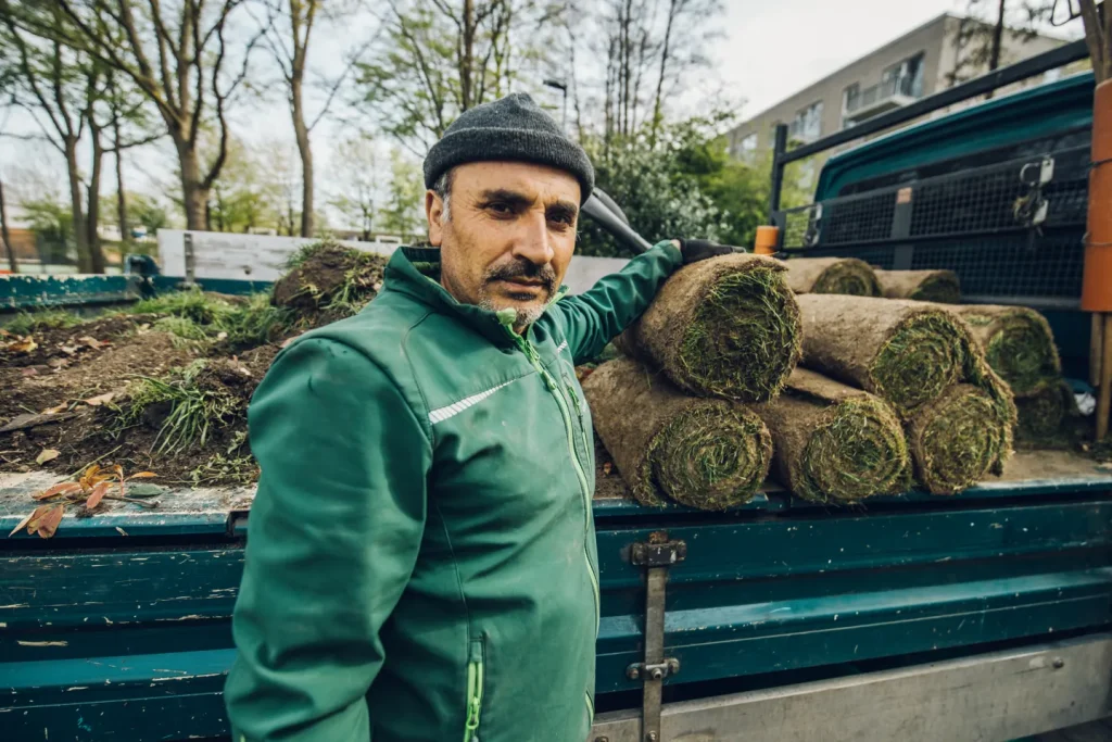 Faik aus unserem Team neben Rollrasen am Firmenfahrzeug